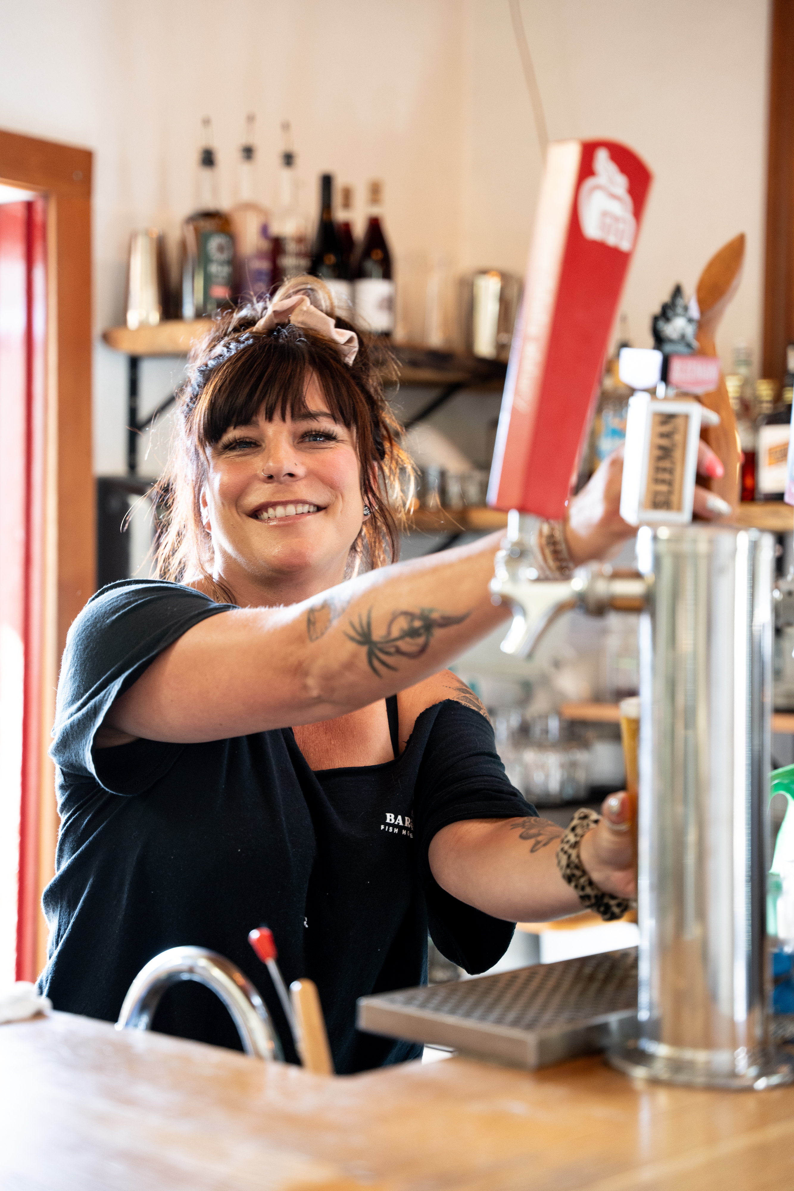 An employee from Bare Bones restaurant in Port Alberni smiles while pouring a beer