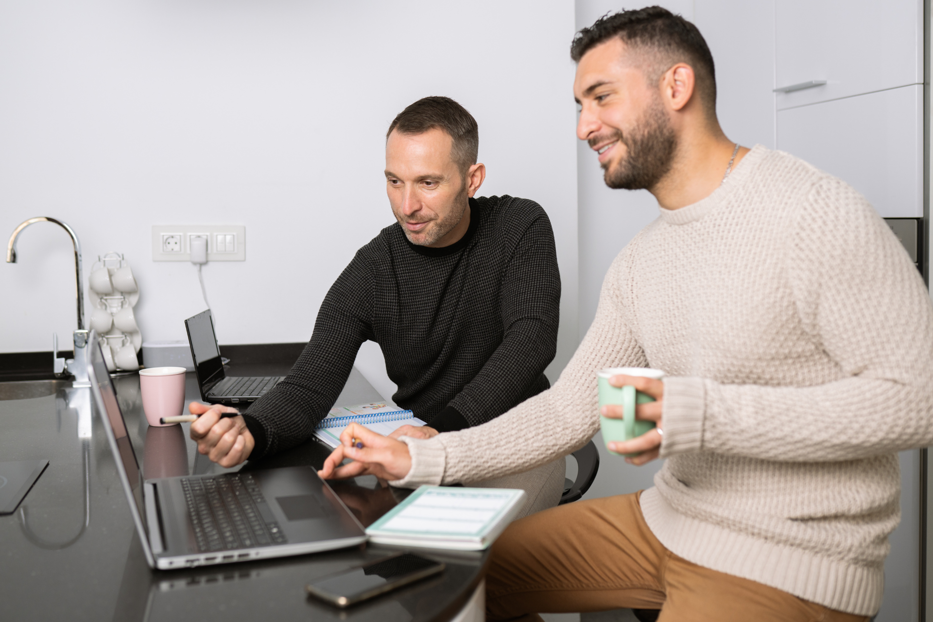 Two men looking at a laptop with one pointing to the screen